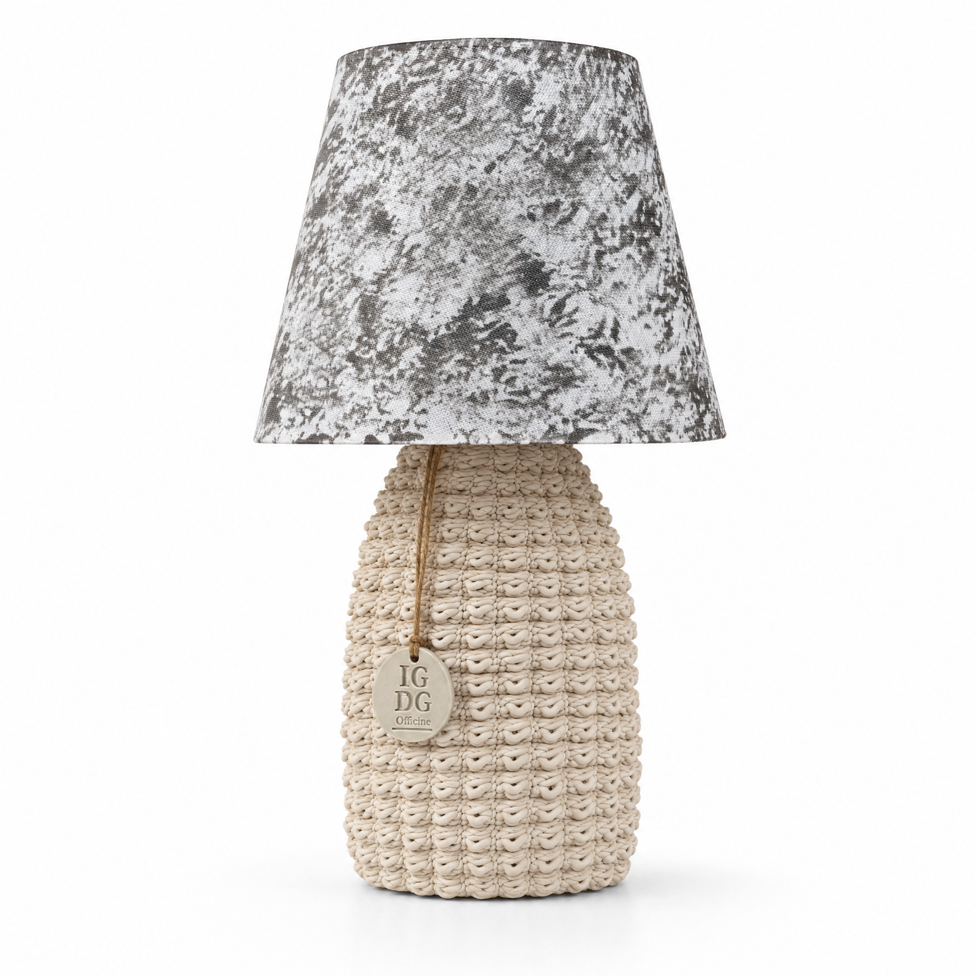 Lume ceramica artigianale Le Officine di Giulia linea Santorini, base in ceramica bianca con texture organica a cordoncino intrecciato e paralume conico in tessuto maculato grigio antracite su bianco, stile batik tie-dye. Medaglione IGDG Officine in ceramica appeso con cordino di juta. Made in Italy. Sfondo bianco, foto prodotto e-commerce.