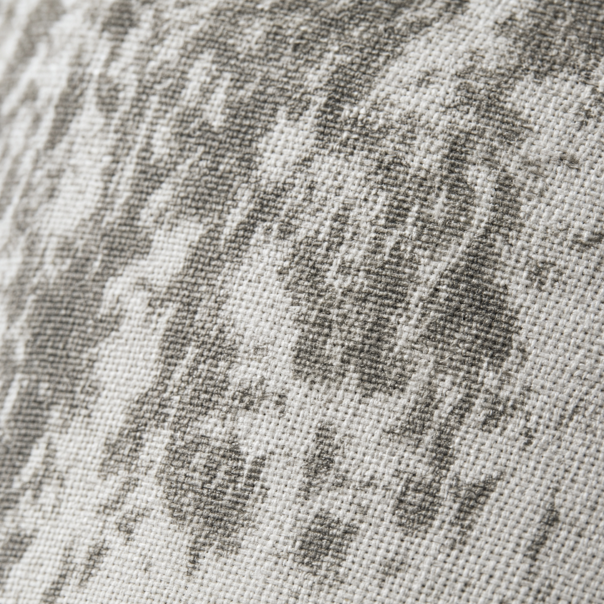 Close-up macro del paralume in tessuto del lume Santorini di Le Officine di Giulia. Il tessuto mostra un pattern maculato grigio scuro e antracite su fondo bianco, con macchie organiche irregolari stile batik/tie-dye. Si distingue la trama del tessuto intrecciato. Dettaglio di qualità artigianale Made in Italy.